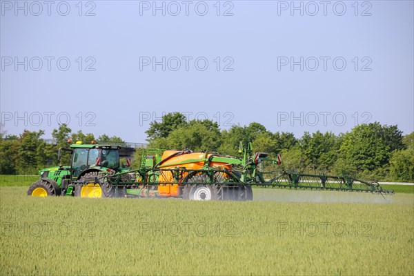A farmer drives his tractor with a crop protection sprayer across his wheat field to combat brown rust and mildew (Hockenheim, Baden-Wuerttemberg)