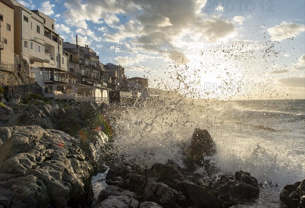 Sea water crashes against the cliffs of the rugged coastline in the town of Cefalu, Sicily, Italy, Europe