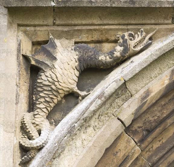 Mythological folklore figure of a griffin dragon carved in stone on the entrance doorway to the church, Peasenhall, Suffolk, England, UK