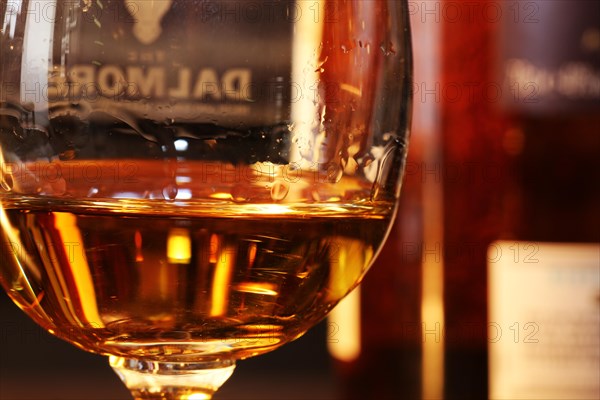 Close-up of a glass of whiskey with a bottle of Dalmore single malt in the background