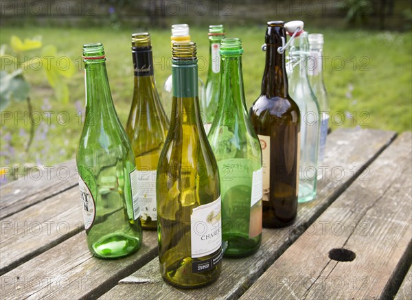 Empty glass bottles standing on a table outdoors in sunshine, UK