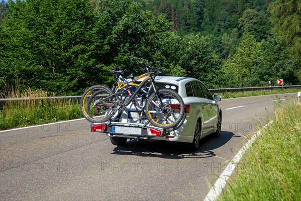 White car with Thule rear bike rack on a country road in Dahner Felsenland Germany