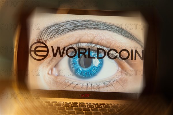 Logo of the new cryptocurrency Worldcoin on a laptop. Anyone wishing to participate in World Coin must register with their biometric data (symbolic image)