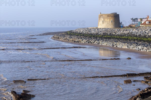 Martello Tower Y low tide protected by rock armour coastal defences, Bawdsey, Suffolk, England, UK, 1940s defences visible