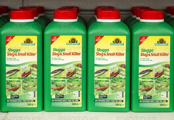 Plastic containers of Neudorff Sluggo slug and snail killer on shelf display in garden centre, UK