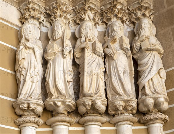 Historic Roman Catholic cathedral church of Evora, Se de Evora, in the city centre, Basilica Cathedral of Our Lady of Assumption. This image shows details of the carved Gothic period Apostles in the main doorway entrance. Marble columns are occupied by huge statues of the Apostles dating from the 1330s