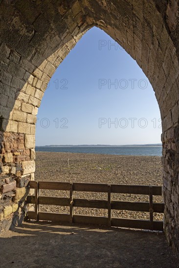 Stone arch of old lime kilns on Holy Island, Northumberland, England, UK view south of coastline