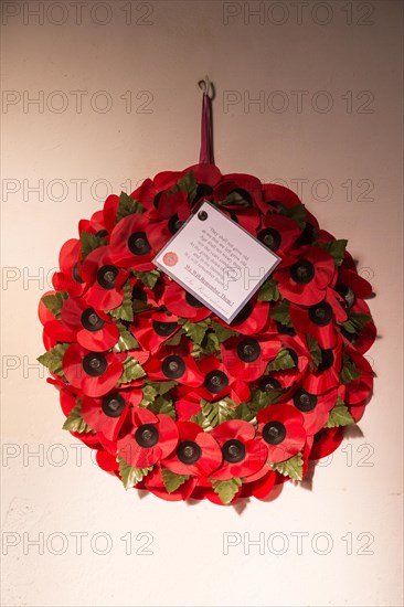 'We will remember them' remembrance day poppy wreath hanging from wall inside the church at South Cove, Suffolk England, UK