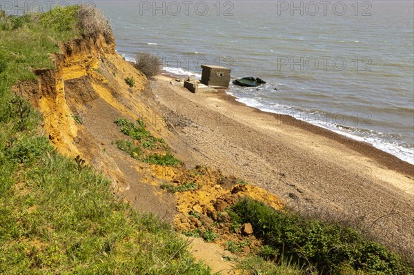 Soft cliffs rapid coastal erosion on North Sea coastline, coast at Bawdsey, Suffolk, England, Uk 1940s pill box