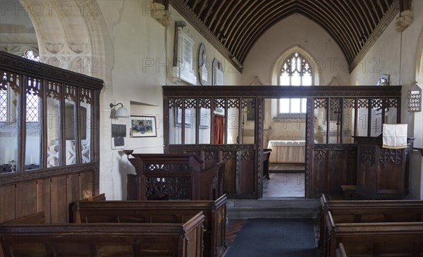 Wooden chancel screen dating from 15th, 16th century looking down to altar and east window inside the church at Charlton, Wiltshire, England, UK
