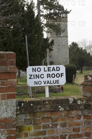 No Lead Zinc Roof No Value sign outside church to deter potential thieves who target churches for their lead roofs, Ellingham, Norfolk, England, UK