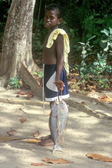 Young carrying fish on the island of La Digue, Seychelles, Africa