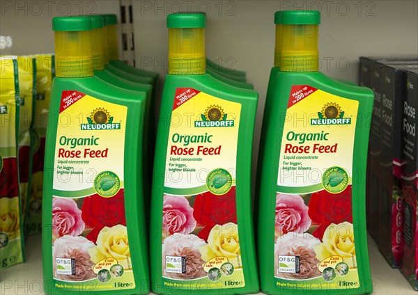 Plastic containers of Neudorff Organic Rose Feed liquid concentrate on shelf display in garden centre, UK