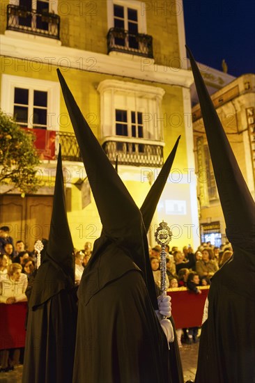 Nazarenos with black robes and typical pointed bonnets, insignia, Semana Santa, procession, night shot, celebrations in Tarifa, Spain, Europe
