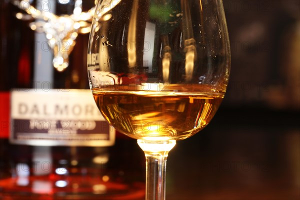 Close-up of a glass of whiskey with a bottle of Dalmore single malt in the background