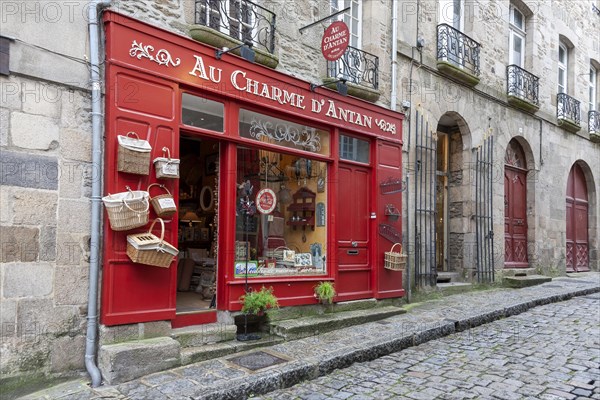 Traditional shop with red facade and baskets on a cobbled pavement, Dinan, Brittany, France, Europe
