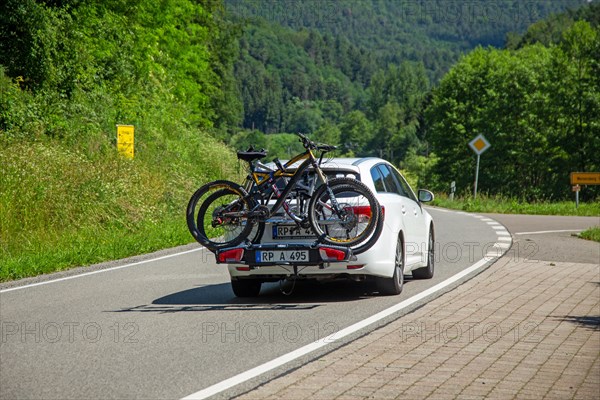 White car with Thule rear bike rack on a country road in Dahner Felsenland Germany