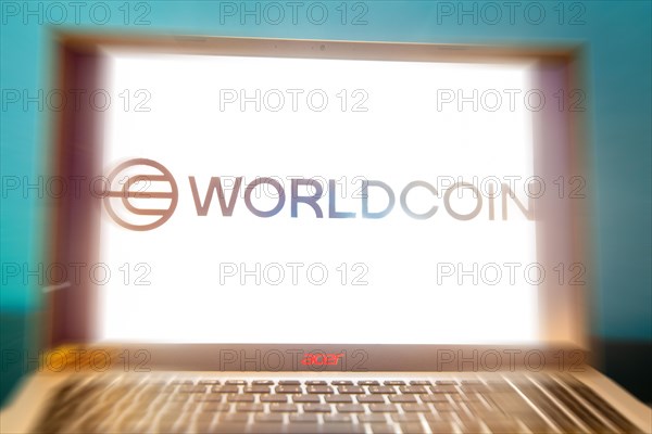 Logo of the new cryptocurrency Worldcoin on a laptop. Anyone wishing to participate in World Coin must register with their biometric data (symbolic image)
