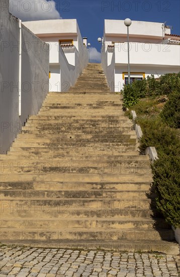 Diminishing converging lines, perspective flight of concrete steps outdoors climbing between two modern whitewashed houses