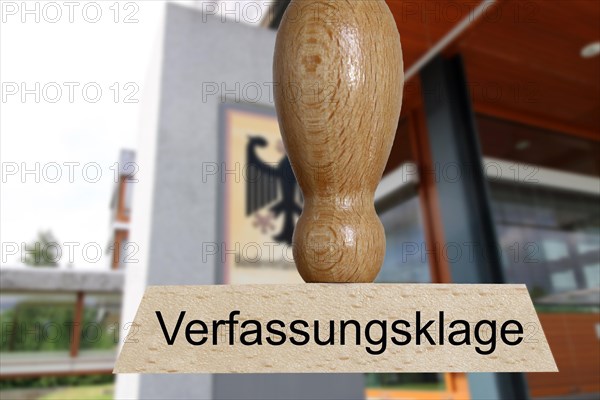 Symbolic image of a constitutional complaint: in the foreground a stamp, in the background the Federal Constitutional Court in Karlsruhe