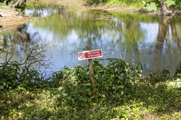 Sign No Tipping or Dumping next to pool of water, UK