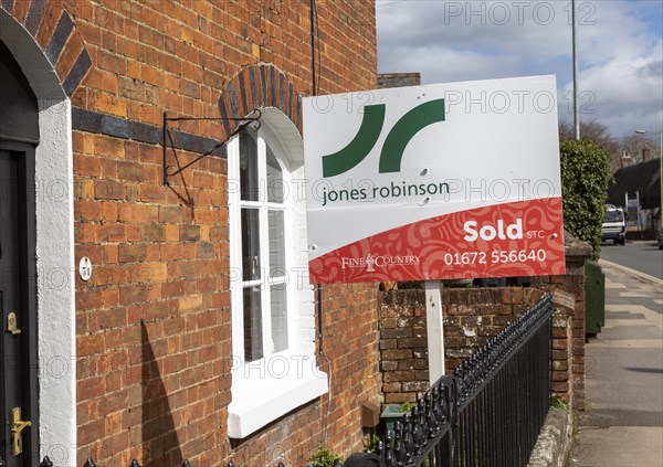Estate agent property sold sign outside red brick historic house, Marlborough, Wiltshire, England, UK