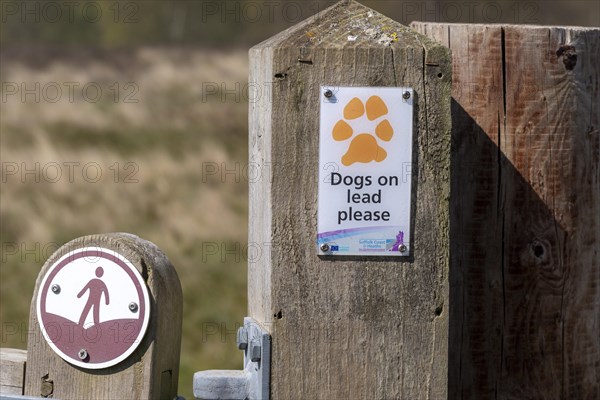 Dogs on Lead Please and footpath walking sign on fencepost, Sutton, Suffolk, England, UK