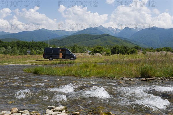 A camper stands on a sunny day next to a river with a view of a mountain range, CarÈ›iÈ™oara River, Cartisoara, FagaraÈ™ Mountains, Fagaras, Transylvania, Transylvania, Transylvania, Ardeal, Transylvania, Carpathians, Romania, Europe