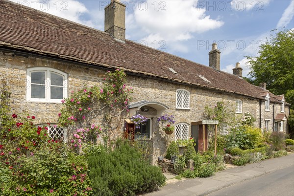 Row of attractive old stone cottages in village of Mells, Somerset, England, UK