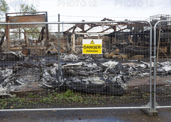 Industrial building destroyed by fire, Hatcher Components Ltd, Parham airfield, Suffolk, England, UK, Danger Asbestos sign