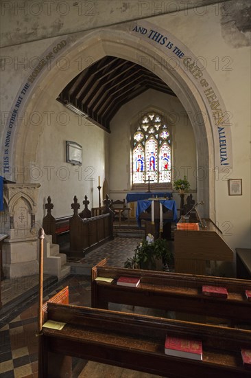 Inside the church at Beechingstoke, Wiltshire, England, UK looking down the nave past the baptismal font to the chancel, altar and east window. The chancel arch dates from 14th century