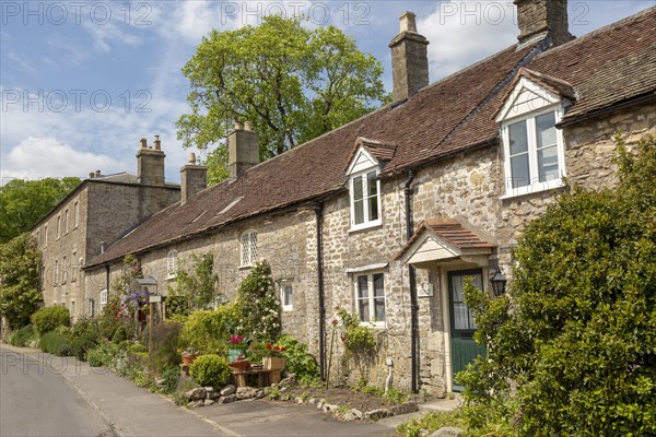 Row of attractive old stone cottages in village of Mells, Somerset, England, UK