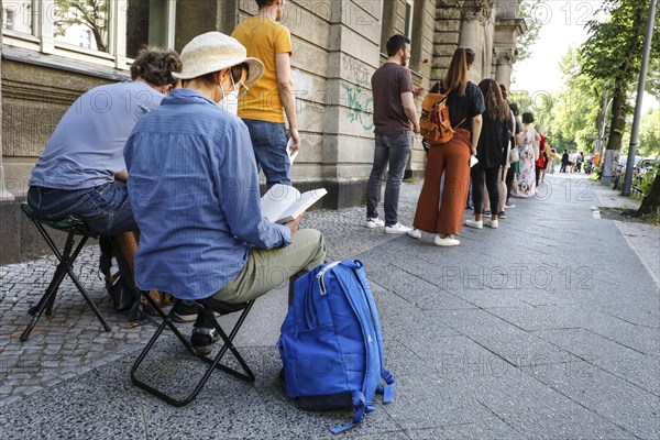 Vaccinated people in a queue sitting on folding chairs. Neighbourhood residents in the Tempelhof Schoeneberg district can get vaccinated free of charge and without registering here, Berlin, 05.06.2021