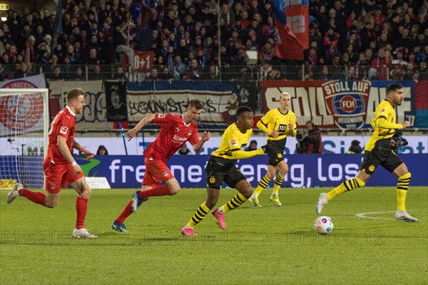 Football match, Lennard MALONEY 1.FC Heidenheim and Jan SCHOePPNER 1.FC Heidenheim left following Youssoufa MOUKOKO Borussia Dortmund on the ball, in the background Emre CAN Borussia Dortmund right, football stadium Voith-Arena, Heidenheim