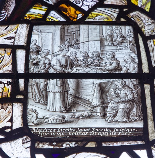 Stained glass window in All Saints church, Eyke, Suffolk, England, UK, Saint Bridget feeding the beggars c17th century