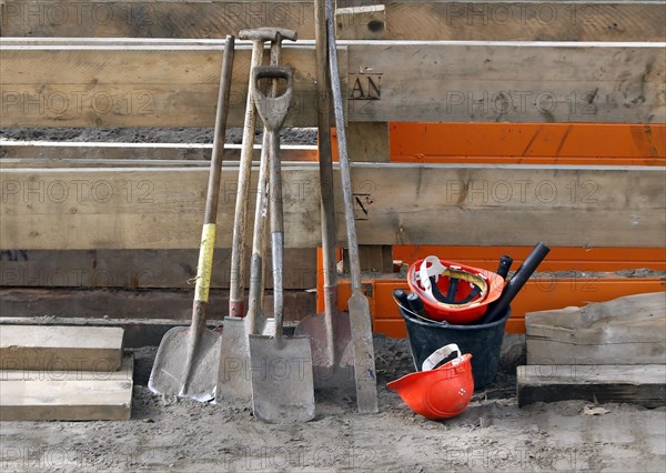 Spades, shovels, hard hats, tools and a bucket lying at a construction site, 10.03.2021