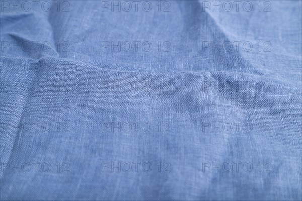 Fragment of smooth blue linen tissue. Side view, natural textile background and texture