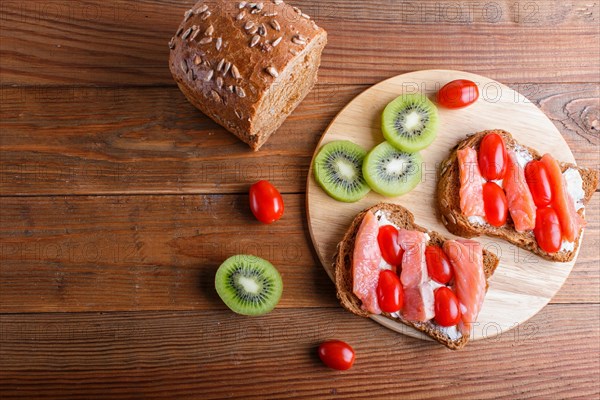 Smoked salmon sandwiches with butter on wooden background. cherry tomatoes. top view, copy space