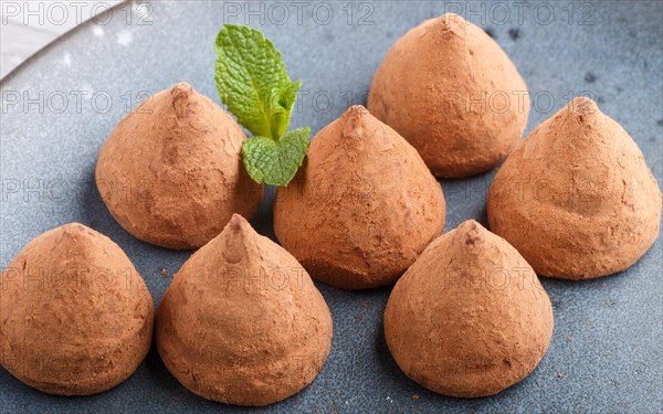 Chocolate truffle on blue ceramic plate on gray concrete background. close up, side view