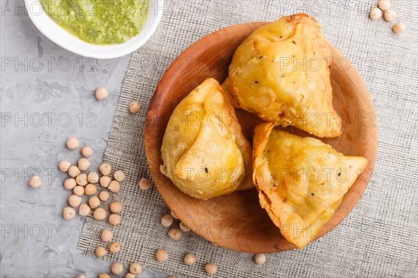 Traditional indian food samosa in wooden plate with mint chutney on a gray concrete background. top view, close up, flat lay