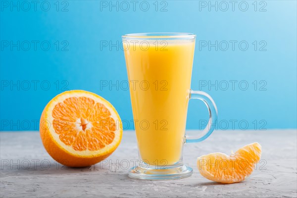 Glass of orange juice on a gray and blue background. Morninig, spring, healthy drink concept. Side view, close up