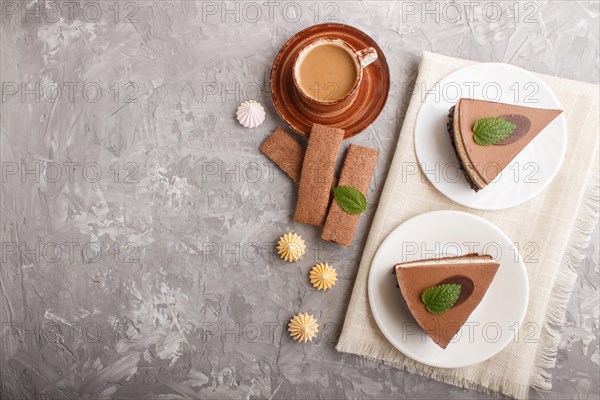 Cake with souffle milk chocolate cream with cup of coffee on a gray concrete background and linen napkin. top view, flat lay, copy space