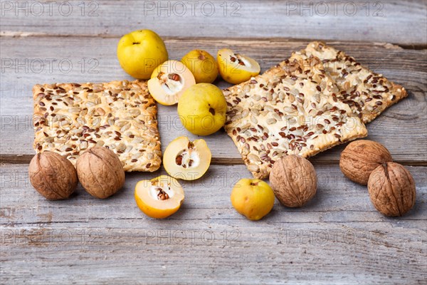 Biscuits with flax, sesame and sunflower seeds and yellow quince fruit on a rustic wooden background