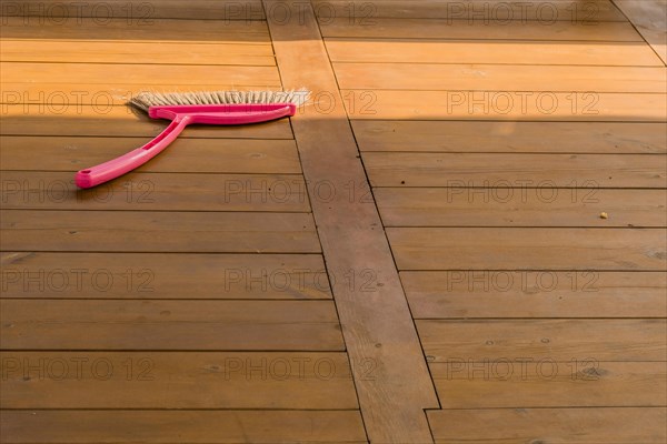 Red plastic broom laying on wooden picnic table in public park in South Korea