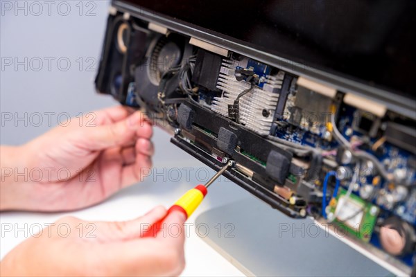 Close-up of an unrecognizable technician fixing computer circuit board of a computer in a workshop