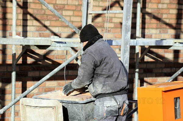 Bricklaying, clinker brick work. Bricklayers clad the facade of a detached house with clinker bricks
