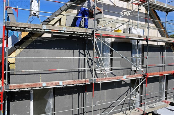 Construction workers insulate a house facade