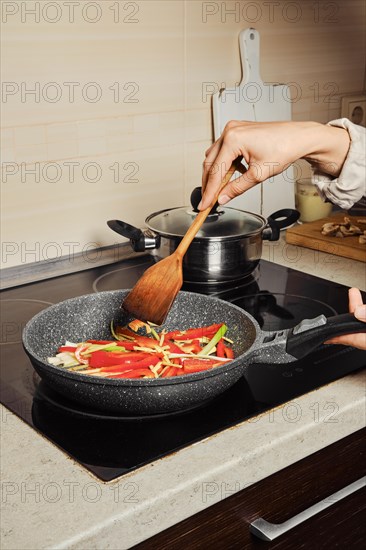 Unrecognizable woman mixing dressing for rice noodles with wooden spatula