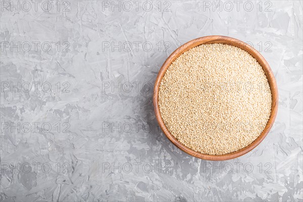 Wooden bowl with raw white quinoa seeds on a gray concrete background. Top view, flat lay, copy space
