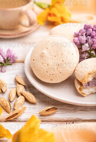 Meringues cakes with cup of coffee on a white wooden background and orange linen textile. Side view, close up, selective focus